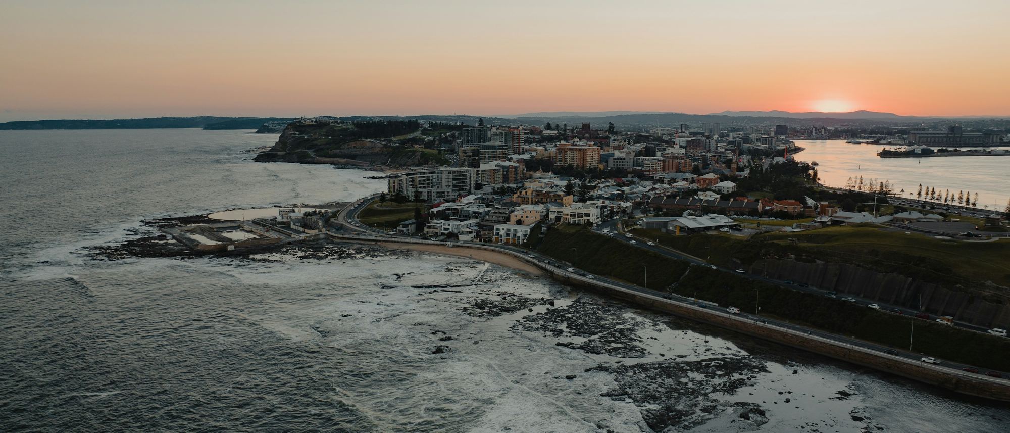 Newcastle East, the Ocean Baths, the city and the harbour from the air at sunset